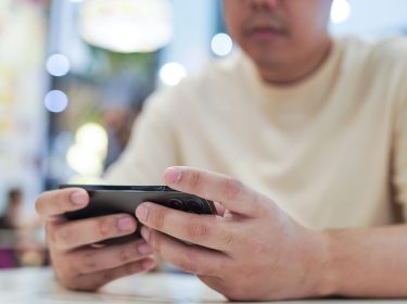 Ein Gamer spielt an seinem Smartphone.