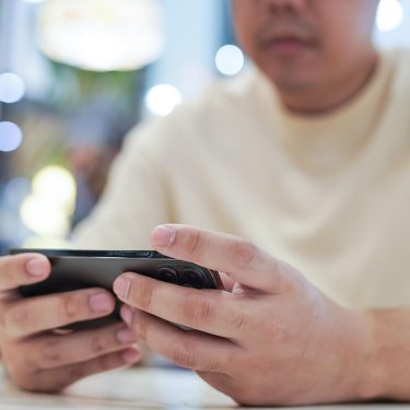 Ein Gamer spielt an seinem Smartphone.