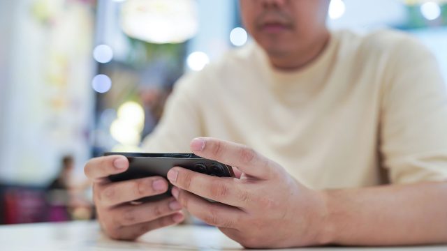 Ein Gamer spielt an seinem Smartphone.