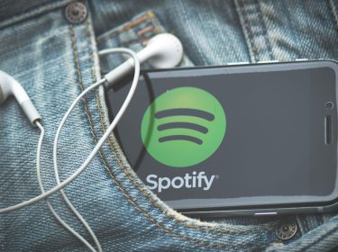 Ein Smartphone mit Spotify steckt in der Hosentasche einer Jeans.