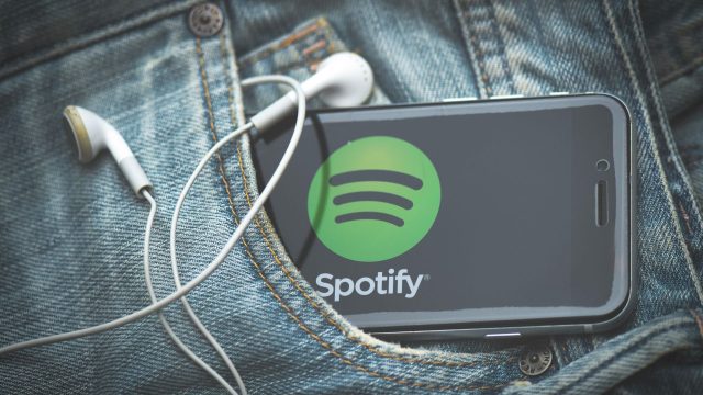 Ein Smartphone mit Spotify steckt in der Hosentasche einer Jeans.