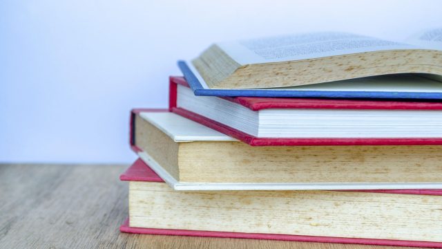 Die Nahaufnahme eines Bücherstapels auf einem Tisch.