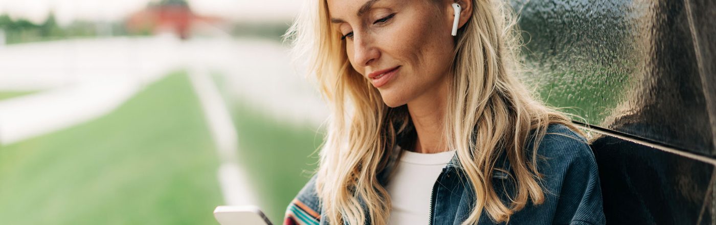 Eine Frau schaut auf ein Smartphone und nutzt AirPods.