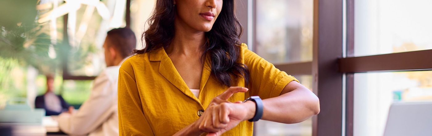 Eine Frau nutzt ihre Smartwatch in einem Büro.