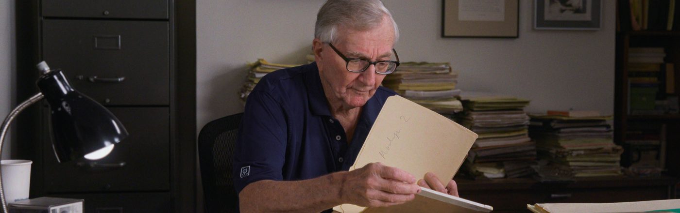 Seymour Hersh sitzt an einem Schreibtisch und blättert durch seine Unterlagen.