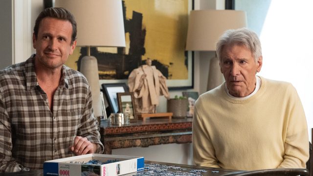 In dieser Szene aus Shrinking Staffel 3 sitzen Jason Segel und Harrison Ford nebeneinander an einem Tisch und arbeiten an einem Puzzle.