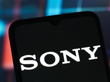 In dem Foto ist ein Handy zu sehen, auf dessen Display das Sony-Logo angezeigt wird.