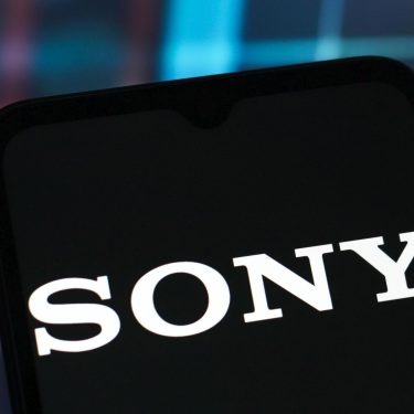 In dem Foto ist ein Handy zu sehen, auf dessen Display das Sony-Logo angezeigt wird.