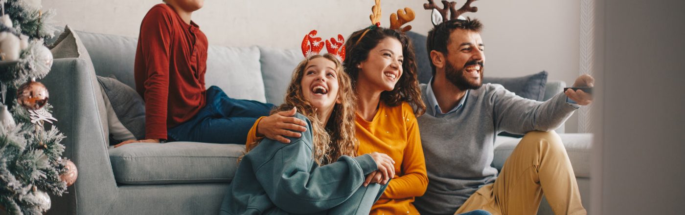 Familie sitzt an Weihnachten gemeinsam vor dem Fernseher und schaut Weihnachtsfilme bei GigaTV