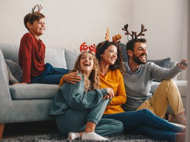 Familie sitzt an Weihnachten gemeinsam vor dem Fernseher und schaut Weihnachtsfilme bei GigaTV