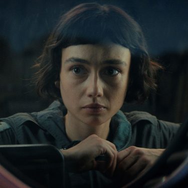 In den besten Serien 2025 siehst du eine Szene aus Alien: Earth. Sydney Chandler als Wendy blickt ernst und konzentriert durch ein rundes Fenster mit technischer Umrahmung.