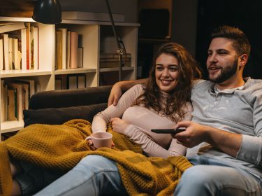 Ein Paar sitzt auf der Couch und schaut Tv.