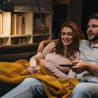 Ein Paar sitzt auf der Couch und schaut Tv.