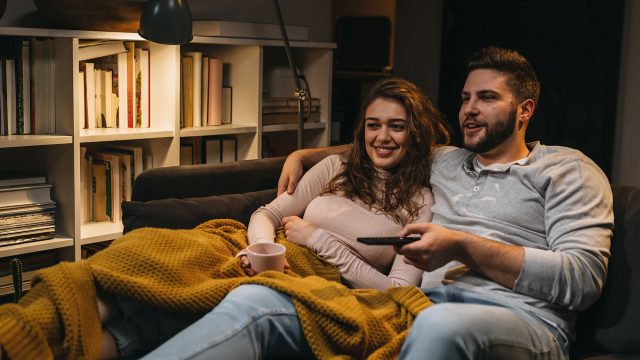 Ein Paar sitzt auf der Couch und schaut Tv.