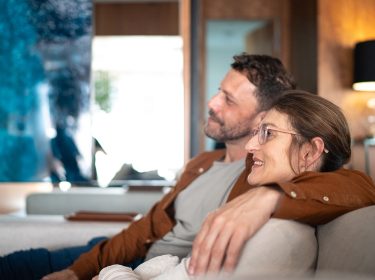 Ein Paar sitzt auf der Couch und schaut Tv.