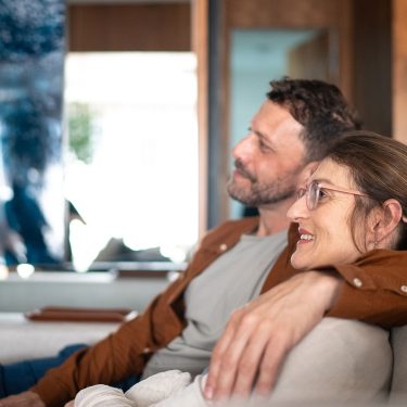 Ein Paar sitzt auf der Couch und schaut Tv.