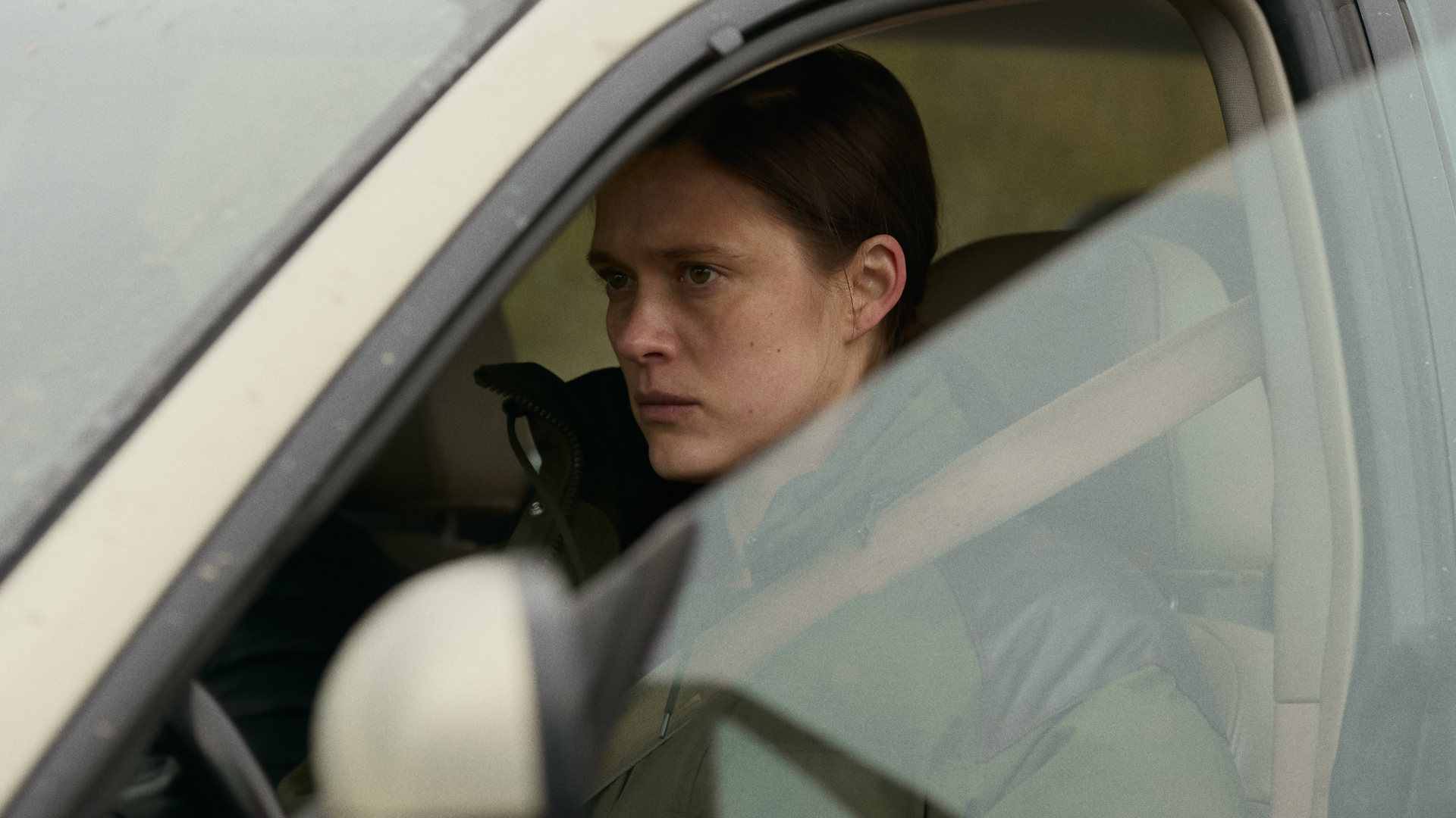 Krista Kosonen als Dani sitzt mit starren Blick im geparkten Auto.