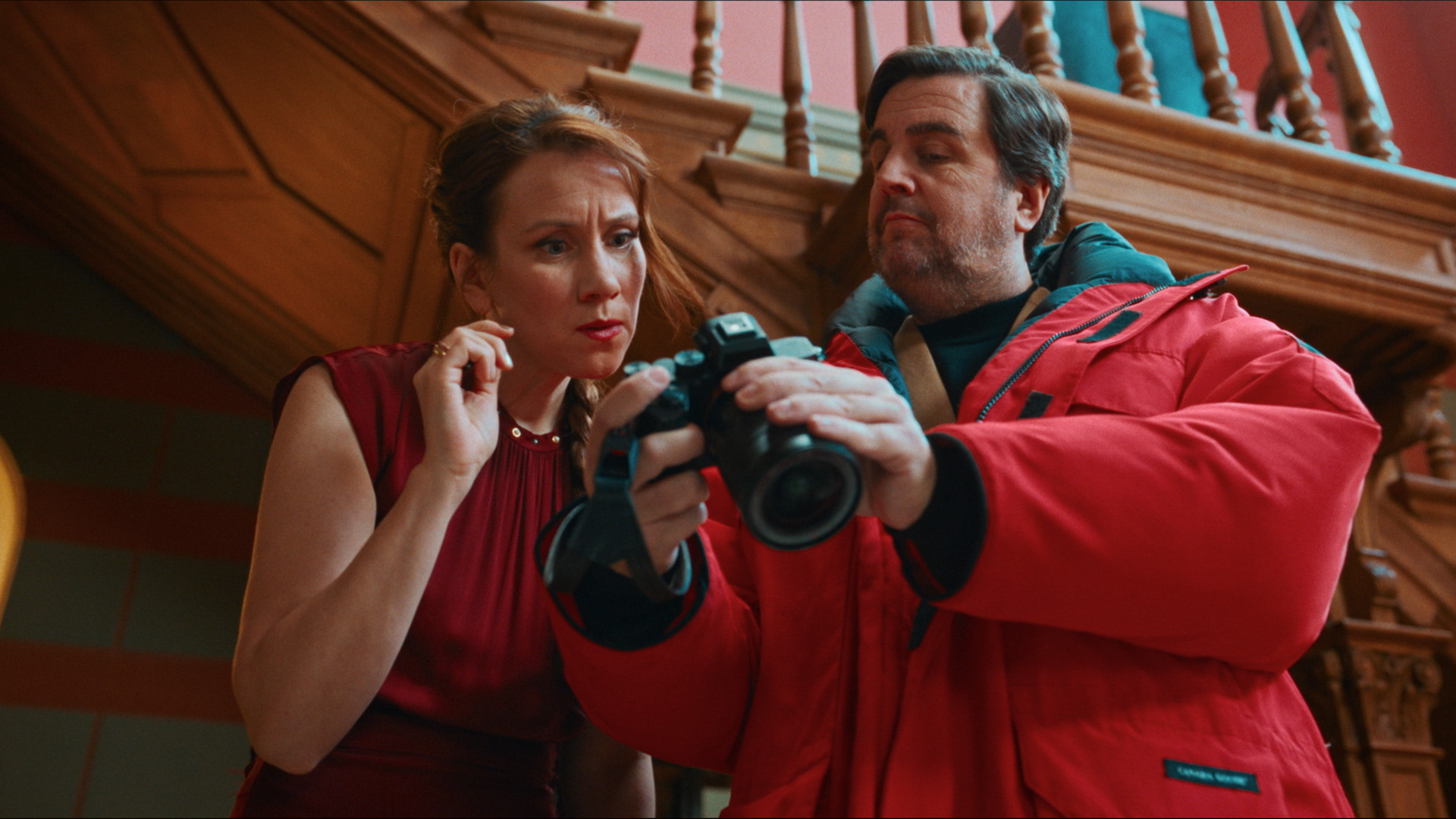 Auf dem Bild in dem Artikel zu "Fabian und Die mörderische Hochzeit" zeigt ein Mann in roter Winterjacke einer Frau eine Kamera.