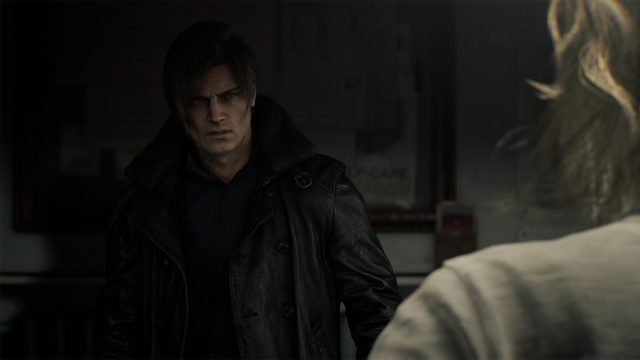 Leon S. Kennedy steht als einer der Resident Evil Requiem Charaktere in einem düsteren Raum. Er trägt eine schwarze Lederjacke mit Fellkragen und blickt ernst und konzentriert nach vorn. Im Vordergrund ist unscharf die Rückansicht einer weiteren Figur zu sehen, was auf eine Konfrontation oder wichtige Unterhaltung hindeutet.