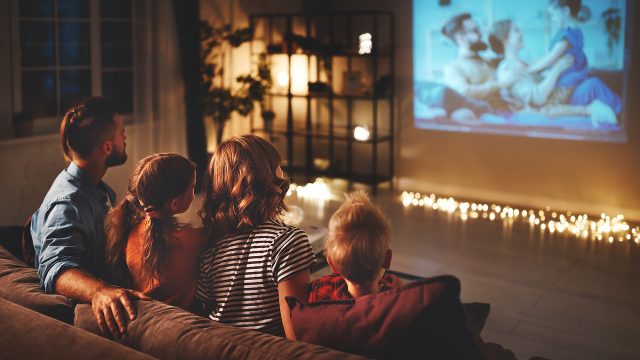 Eine Familie sitzt auf der Couch und schaut TV.