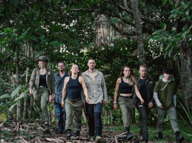 Auf dem Bild zu 7 vs. Wild Gewinner:innen sind sieben Teilnehmende im Dschungel zu sehen. Von links nach rechts: Jeannine Michaelsen, Joe Vogel, Fibii, Lucas „Avive“ Michels, Imke Salander, Kris Grippo und David Leichtle. Alle tragen Outdoor-Kleidung und wirken fokussiert und entschlossen, während sie durch dichtes Grün marschieren.