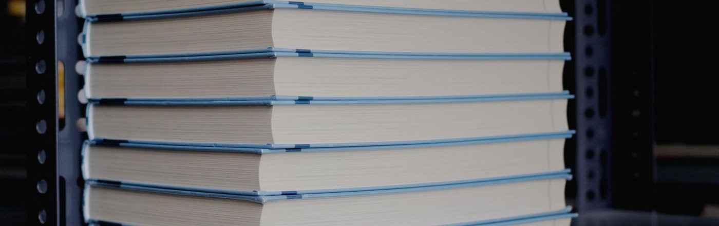 Bücher stehen gestapelt in einem Regal.