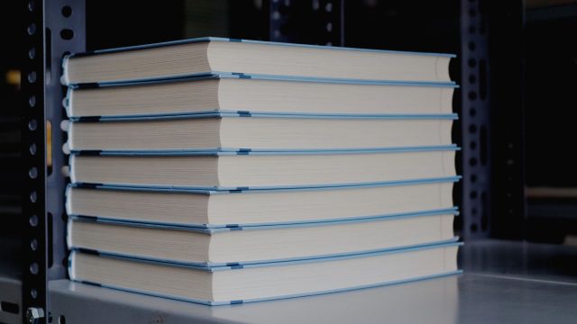 Bücher stehen gestapelt in einem Regal.