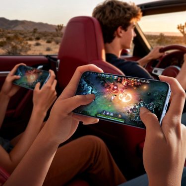 Auf der Rückbank eines Cabrios spielen zwei junge Frauen mit ihren Smartphones