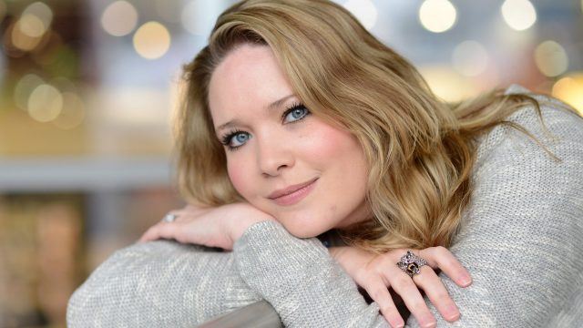 Auf dem Bild zur Crescent City-Reihenfolge ist die Autorin Sarah J. Maas in einem ruhigen Porträt zu sehen. Sie lehnt entspannt an einer Brüstung, trägt einen hellen Strickpullover und einen auffälligen Ring. Ihr freundlicher Blick und das weiche Bokeh im Hintergrund erzeugen eine warme, inspirierende Stimmung, die Kreativität und literarische Nähe vermittelt.