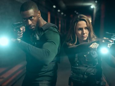 Aldis Hodge als Detective Alex Cross und Alona Tal als Special Agent Kayla Craig. Beide stehen mit gezogener Pistole und einer Taschenlampe im Dunkeln.