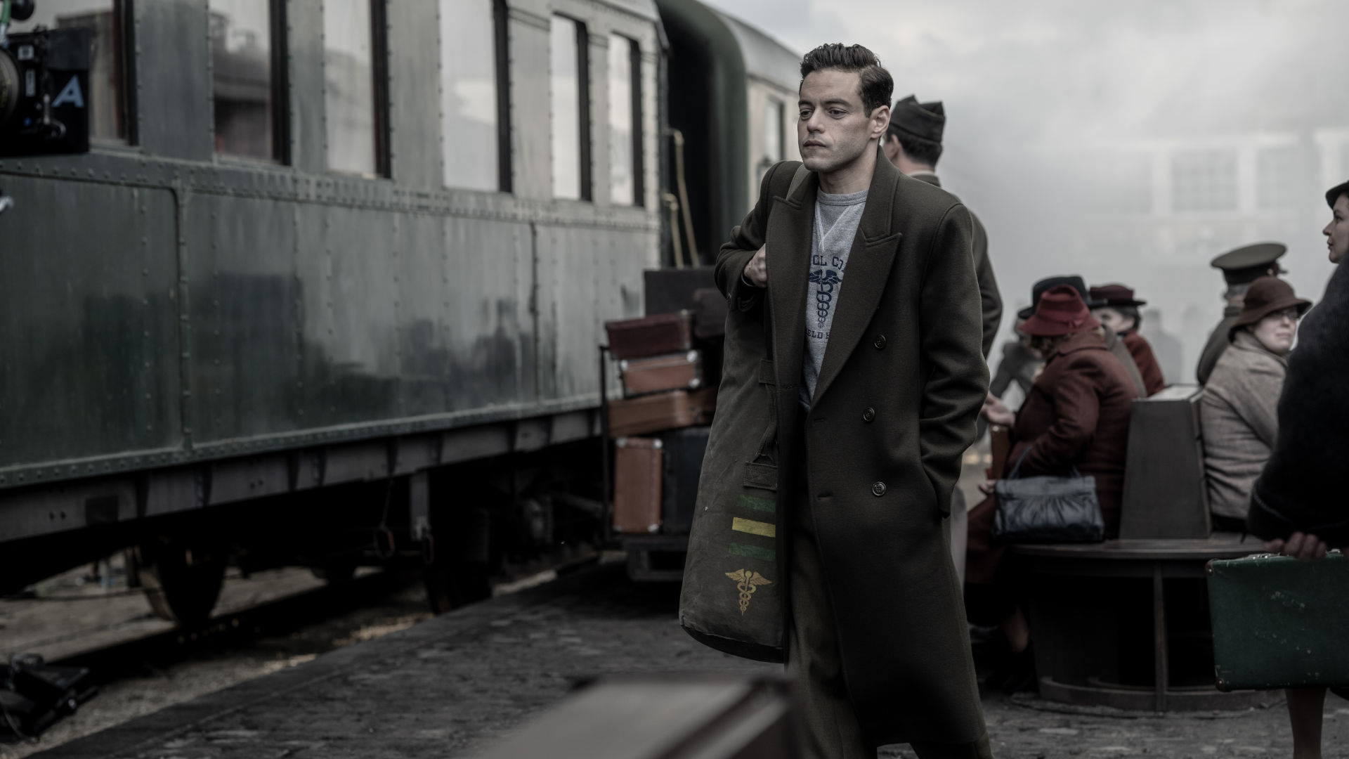Douglas Kelley (Rami Malek) steht an einem Bahnsteig neben einem Zug.