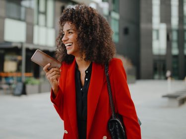 Auf dem Bild in dem Artikel zu den Vodafone Wechselwochen ist eine Frau mit einem roten Blazer und einem Handy zu sehen.
