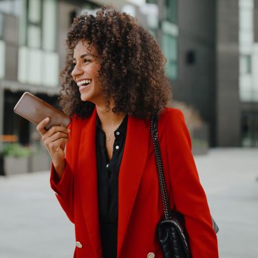 Auf dem Bild in dem Artikel zu den Vodafone Wechselwochen ist eine Frau mit einem roten Blazer und einem Handy zu sehen.