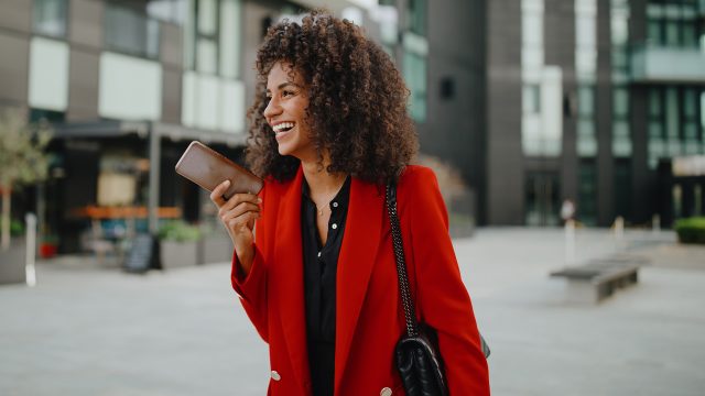 Auf dem Bild in dem Artikel zu den Vodafone Wechselwochen ist eine Frau mit einem roten Blazer und einem Handy zu sehen.