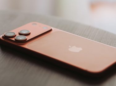 iPhone 17 Pro Max in Orange liegt auf einem Holztisch.