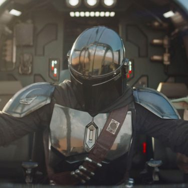 Der Mandalorianer Din Djarin und sein Schüler Grogu sitzen im Cockpit eines futuristischen Fahrzeuges.