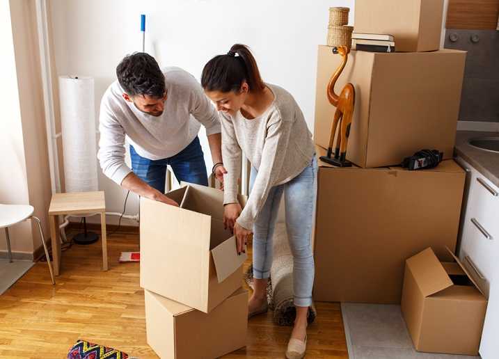 A couple i packing up cardboard boxes